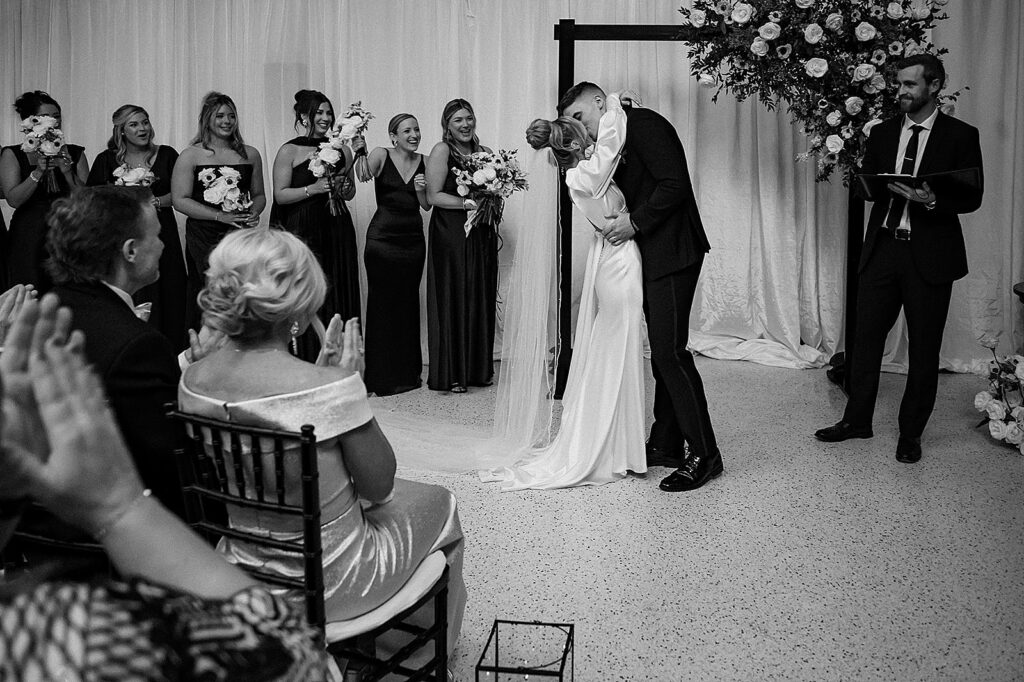 A bride and groom kiss at the end of their wedding ceremony.