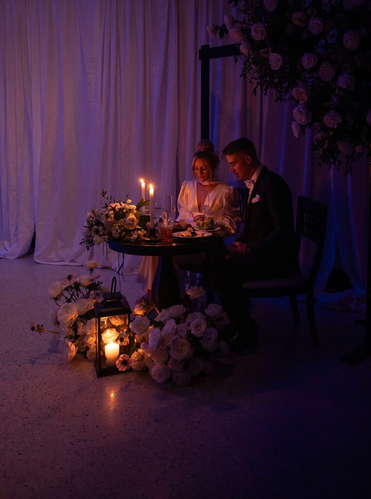 A bride and groom sit at a candlelit sweetheart table at their wedding reception in Louisville.