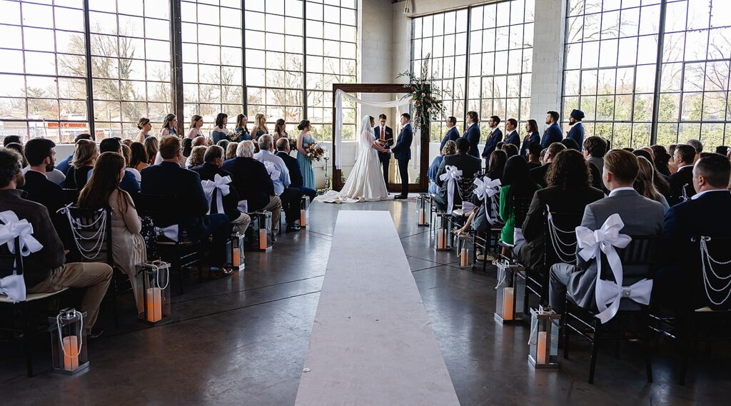 A bride and groom hold hands during a wedding ceremony inside a Louisville wedding venue.