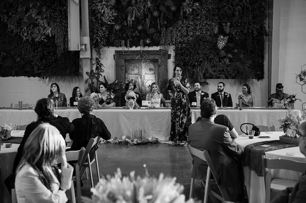 Wedding guests listen to a wedding speech in a reception hall.