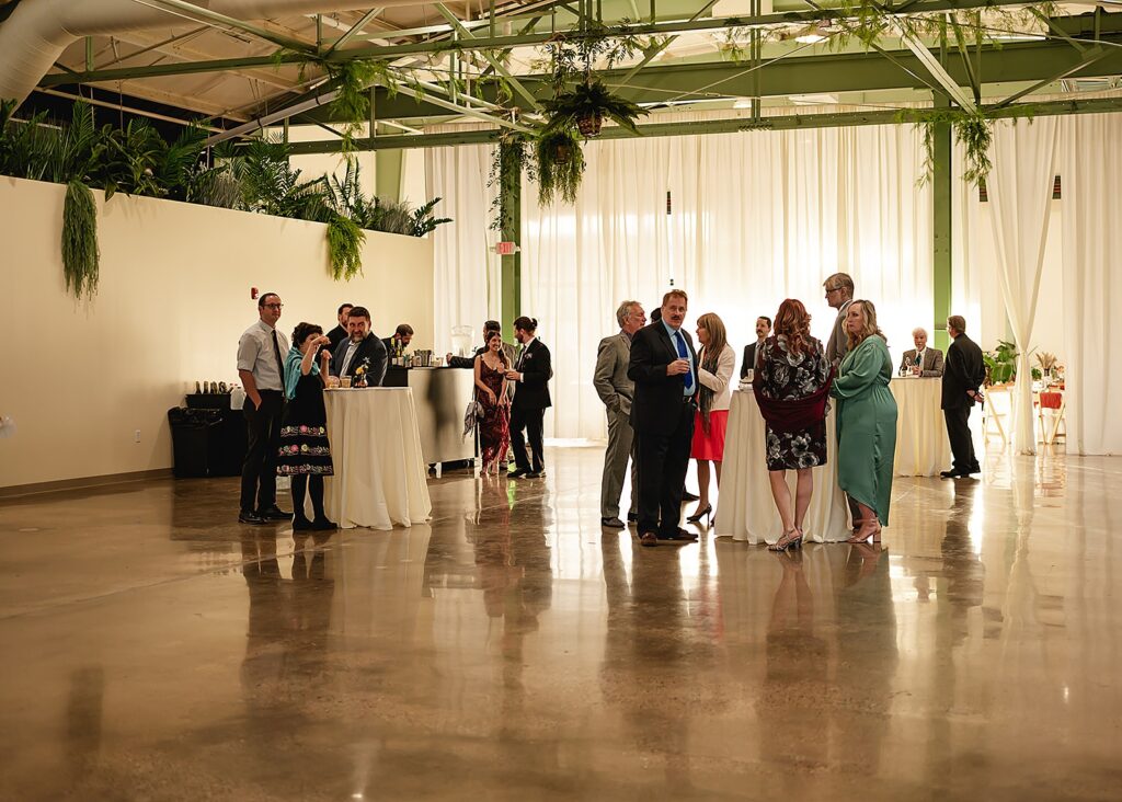 Wedding guests gather around cocktail tables inside a Louisville wedding venue.