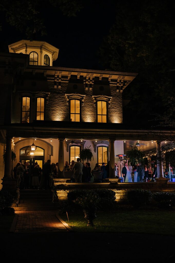 Colorful lights illuminate a porch where wedding guests dance.