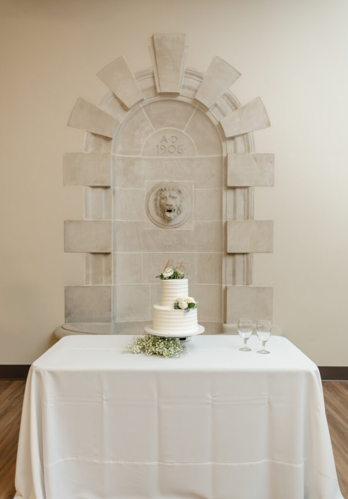 A simply elegant stone arch with a lion head in the center makes the perfect backdrop for the clean white wedding cake