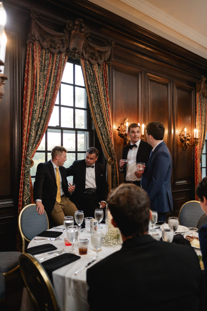 A candid photo of guests conversing in a historic marbled wood room inside Gardencourt