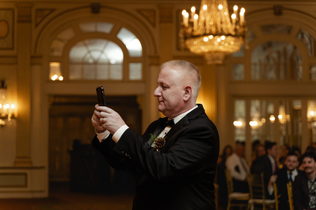 Matthew's father takes a photo with his phone of his son and wife dancing together