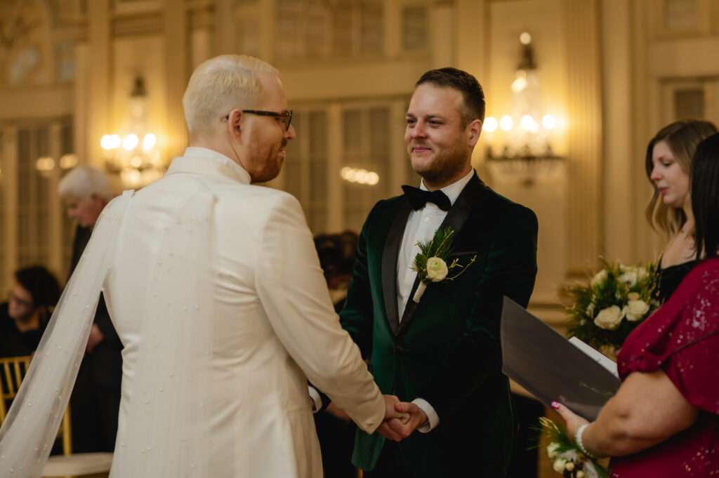 The grooms hold hands at the altar as their ceremony begins