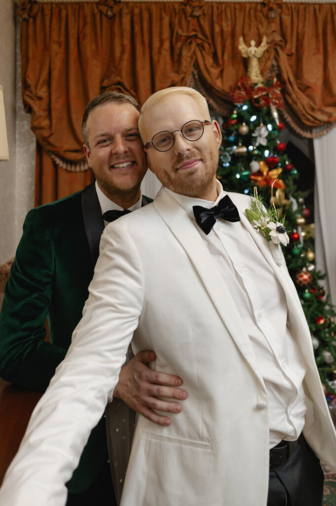 The grooms look classy as they pose for a photo in front of one of the many Christmas trees at the Brown Hotel