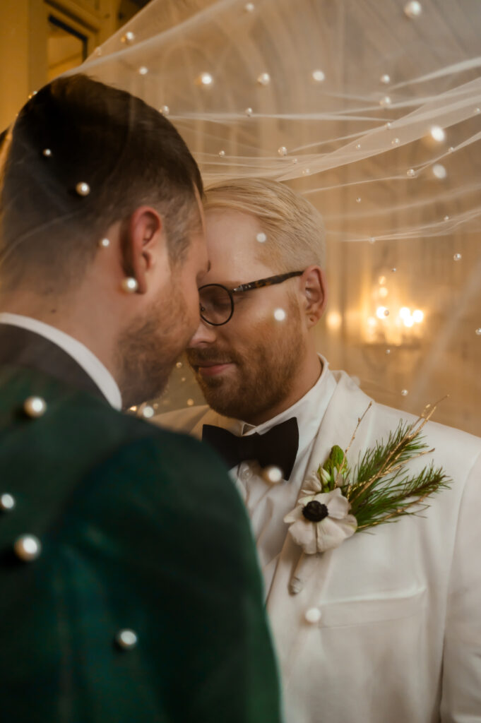 The newlyweds share a close embrace as the pearled veil covers them, giving the illusion of snowflakes falling