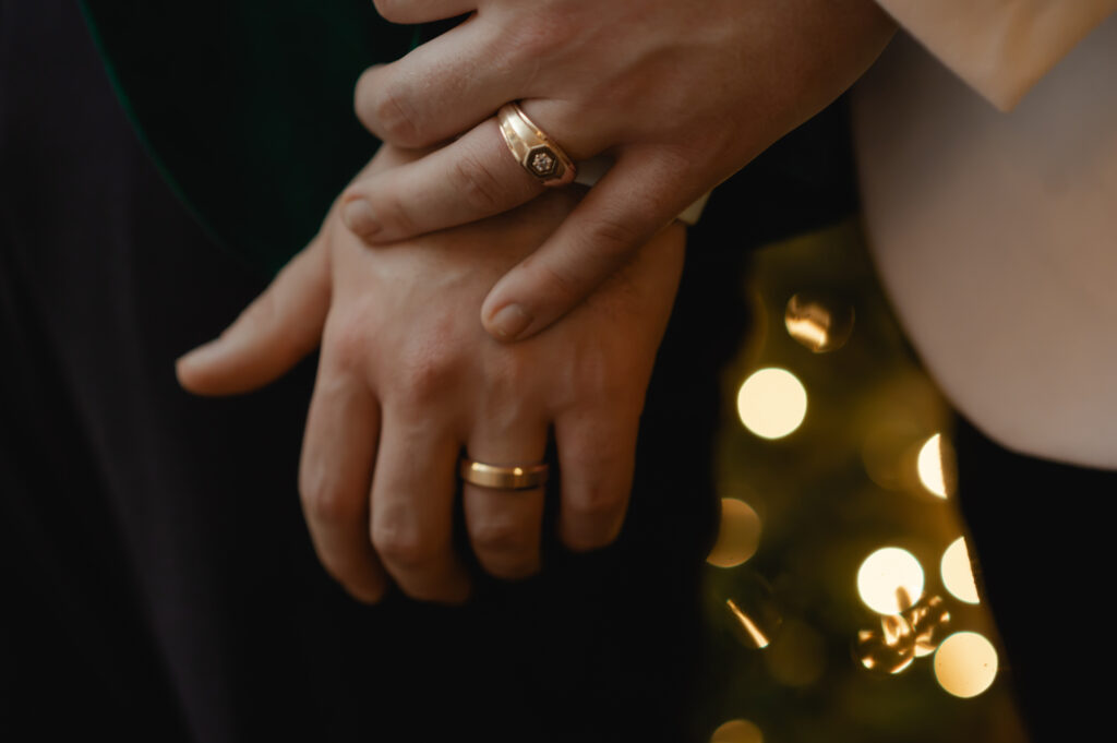 A closeup photo shows both grooms' hands with their wedding bands on