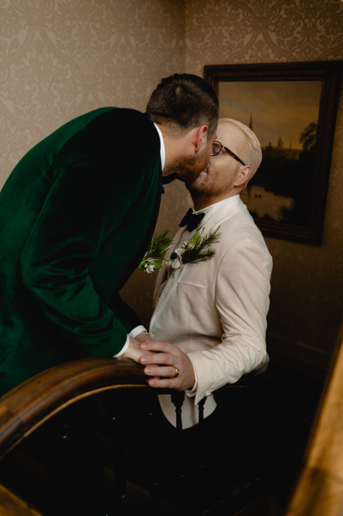 The grooms share a kiss on the staircase of the Brown Hotel