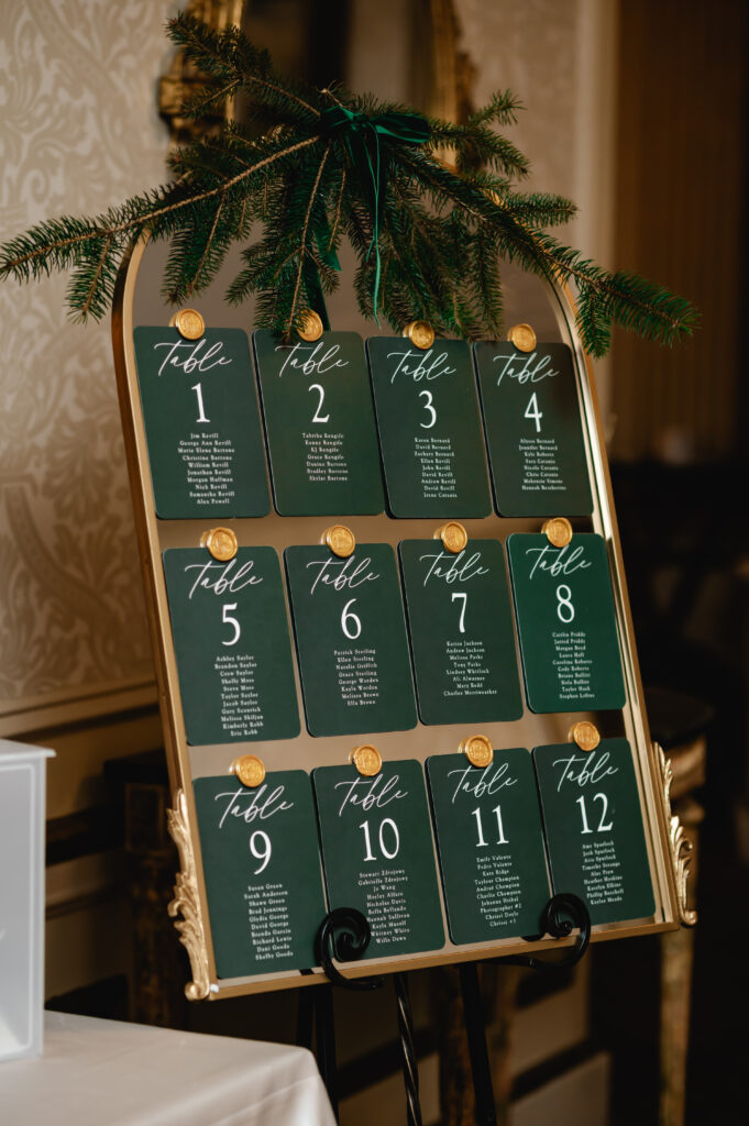 A gold framed mirror holds the emerald green seating chart cards with gold wax seals