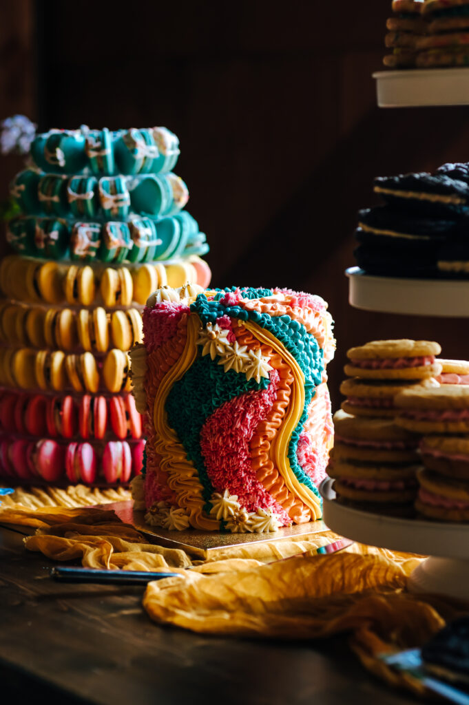 A funky rainbow, 70s inspired "rug cake" stands out with a tower of ombre macarons behind it