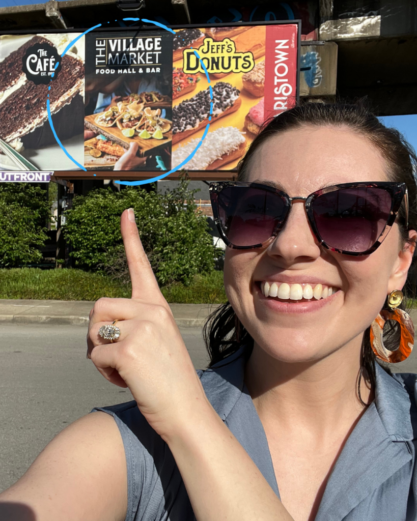 A selfie of the photographer in front of the billboard where her photo is featured.