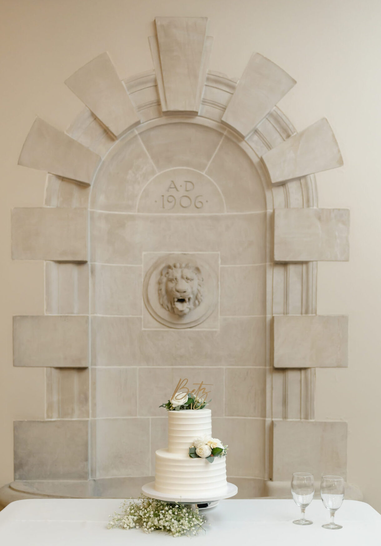 A simply elegant stone arch with a lion head in the center makes the perfect backdrop for the clean white wedding cake