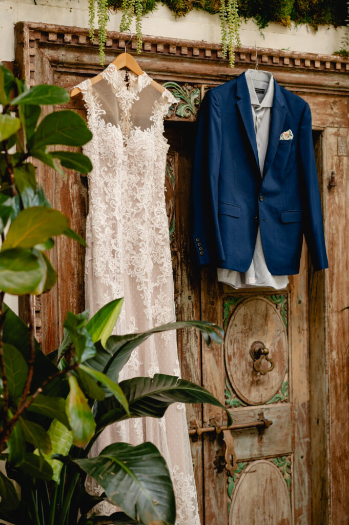 The bride and groom's attire hangs on a rustic wooden door.