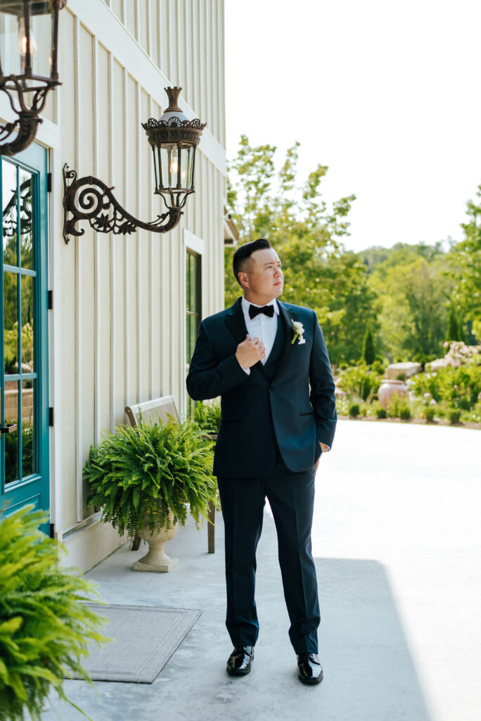 A groom poses stoically outside of Hazelnut Farm