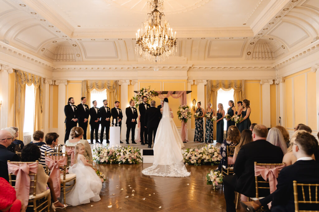 A bride and her father approach her groom in the grand ballroom of the Pendennis Club