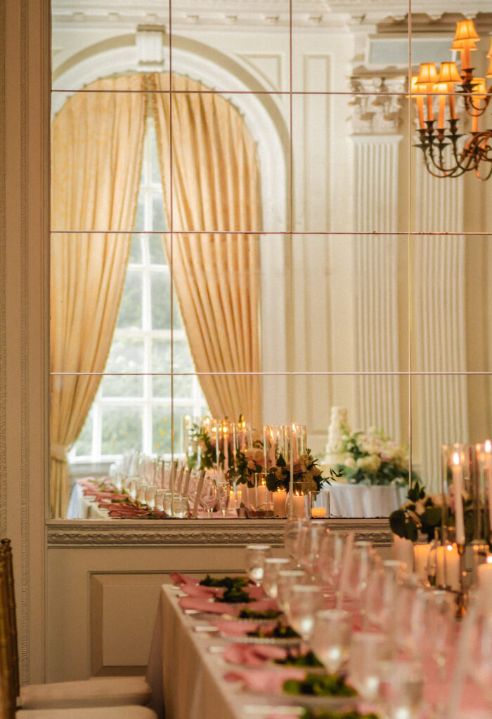 A mirror reflection shows the head table decorated impeccably with tall candles.