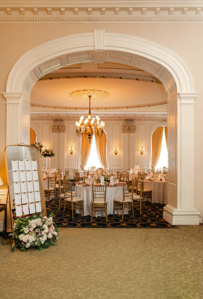 A stunning view of the ballroom decorated for the wedding dinner from outside of the arch