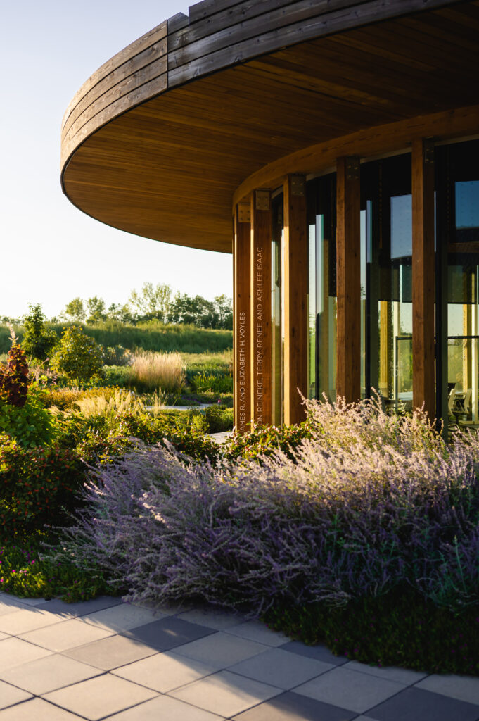 A photograph of the Graeser Education building at the Waterfront Botanical Gardens shows the unique architecture and the lush gardens