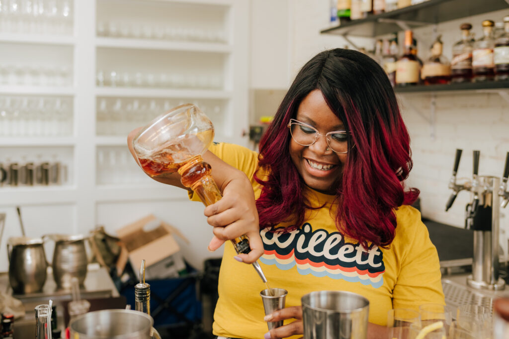 A smiling bartender pours drinks for an event