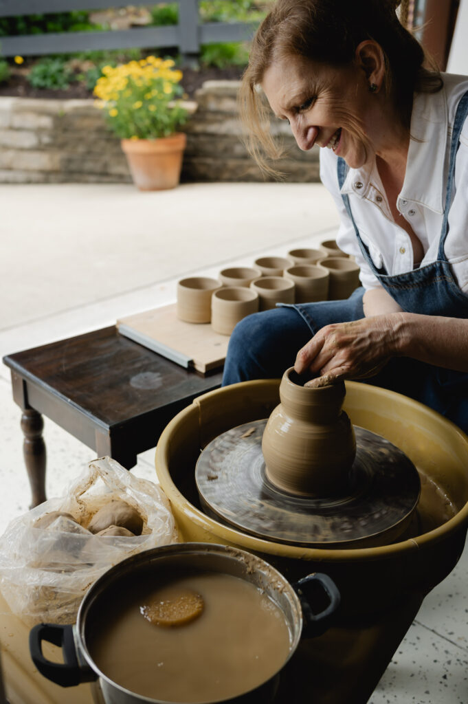 A ceramics artist throws pottery in her home studio