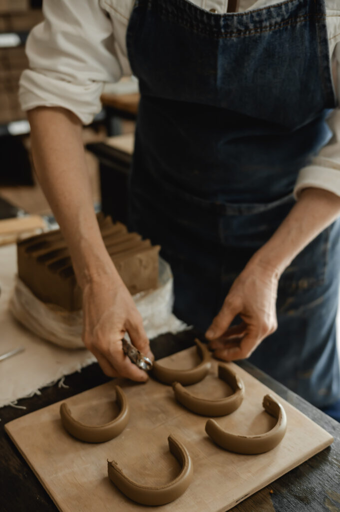 A ceramics artist shapes handles for mugs she is making