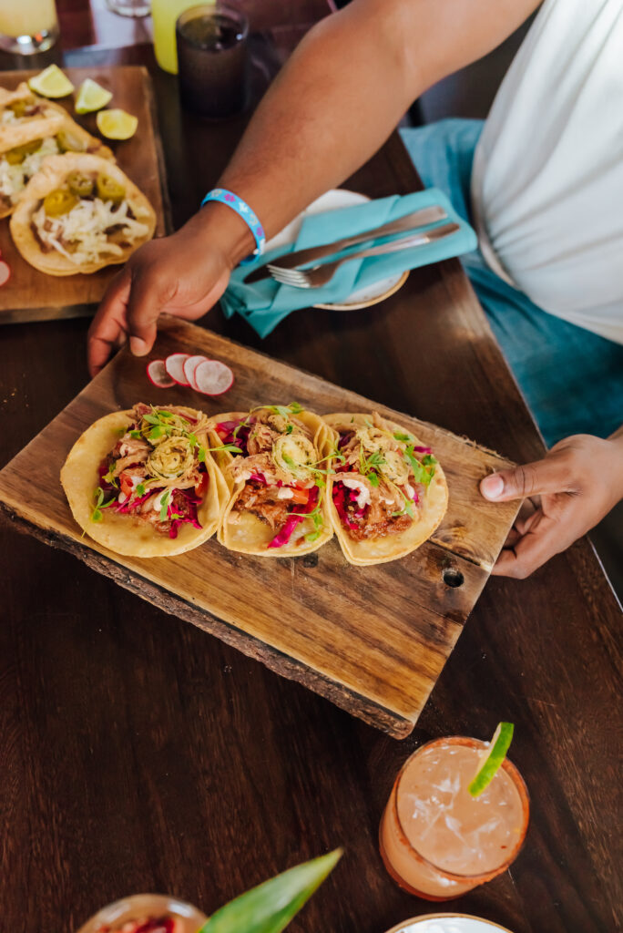 Someone passes a plate of tacos across the table