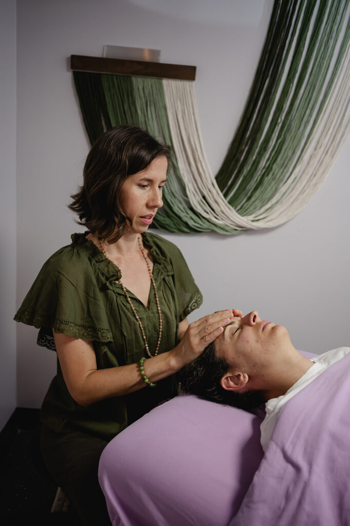 Ana concentrates as she rests her hands on her client's forehead in her reiki studio.