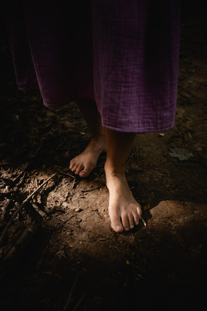 A ray of golden light strikes across the forest floor and illuminate Ana's foot taking a determined step forward.